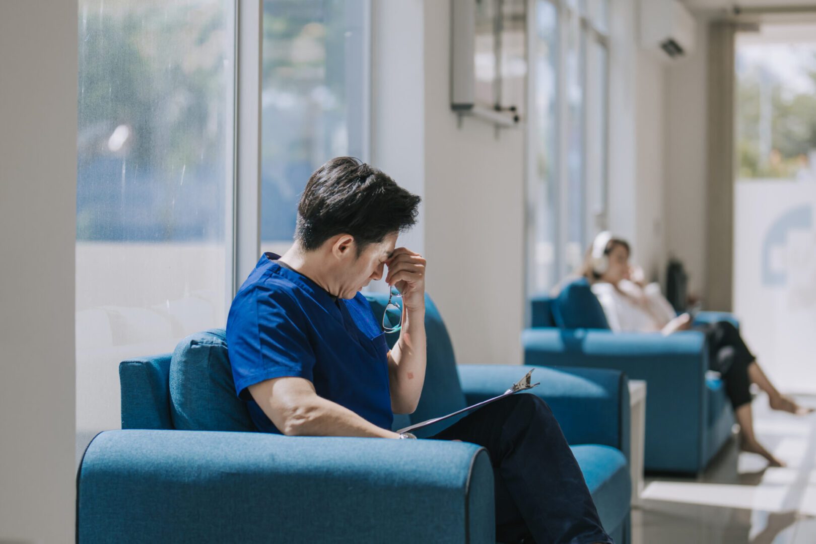 Man sitting, looking stressed in waiting area.