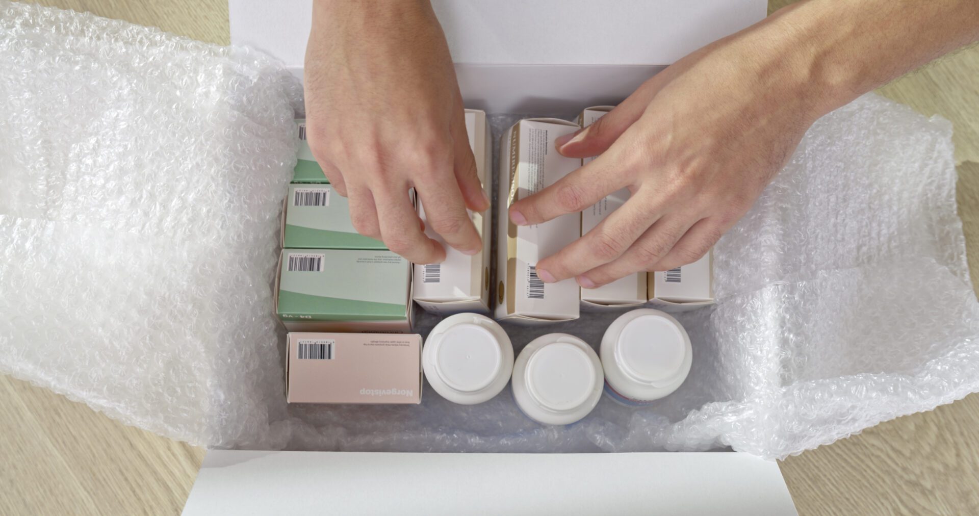 Hands organizing medication boxes in packaging.