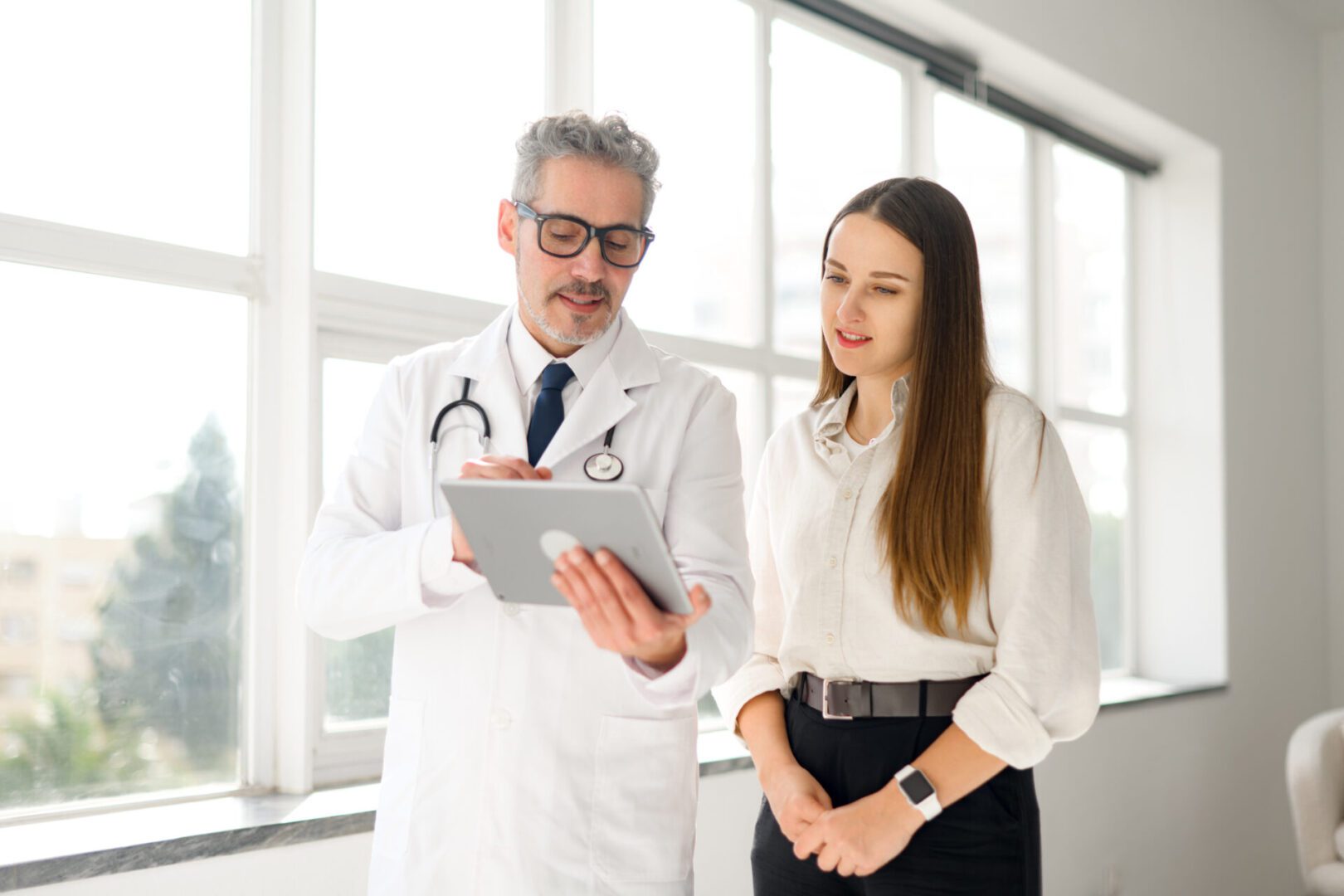 Doctor and woman discussing on tablet.