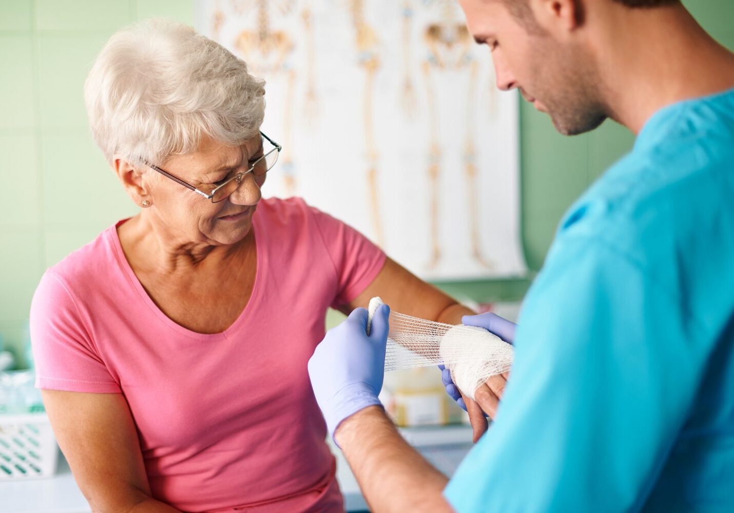 Nurse bandaging elderly woman's arm