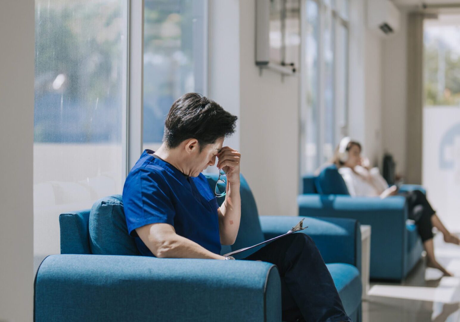 Man sitting, looking stressed in waiting area.